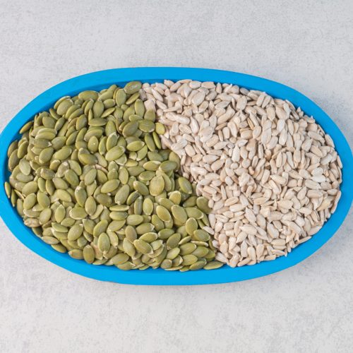 Green pumpkin and sunflower seeds in a platter. High quality photo
