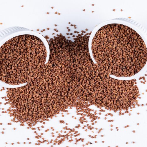 Buckwheats in bowls and in front of bowls on a white background. high angle view.