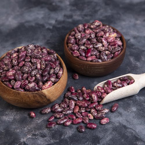 Wooden bowls full of raw grains of dried beans on a black background . High quality photo